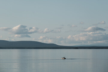 Naklejka premium A fisherman sits in a boat in the middle of a lake
