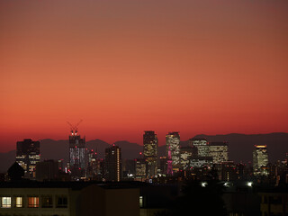鮮やかな夕焼けと名古屋市の駅前ビルの夜景