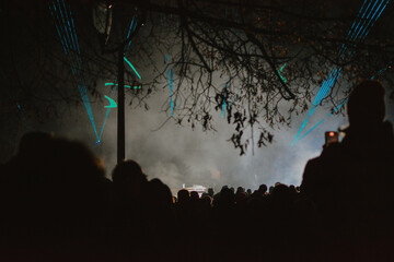 Street concert of a musician in the evening on stage with multi-colored spotlights and audience