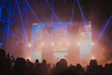 Street concert of a musician in the evening on stage with multi-colored spotlights and audience