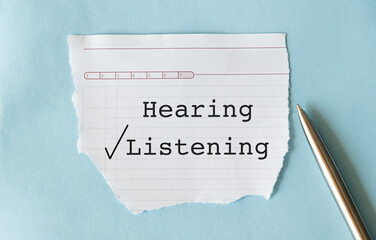 Pen on white paper with check box HEARING and LISTENING, concept of choose to listen than just...