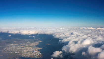 Fototapeta premium A stunning aerial view shows fluffy white clouds floating above Earth's landscape against a deep blue sky.