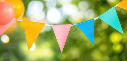Colorful party pennant banners hanging outdoors with green bokeh background