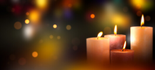 four burning candles at the edge of blurred bokeh light background, merry christmas greeting card...