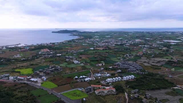 It's winter under Mt. Sanbang on Jeju Island, but it's a view of the village with green rice paddies and fields. Filmed with drones