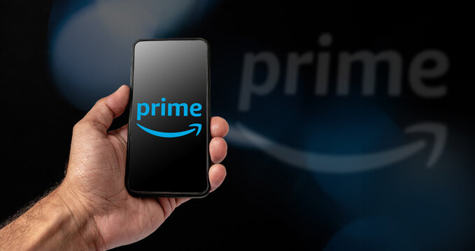 Milan, March 2024 - Male hand holding a smartphone with Prime logo on display, dark background