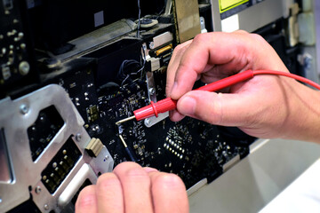 computer technician technician A laptop motherboard repairman is using an IC meter to look for...