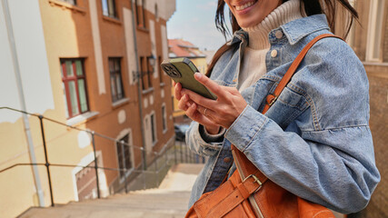 Fototapeta premium Woman enjoying a sunny day while checking notifications on her smartphone.