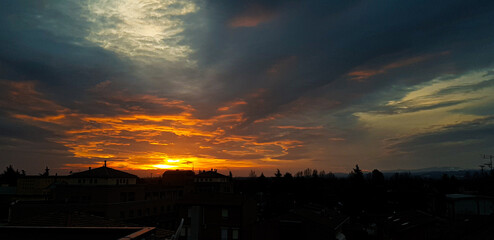 A beautiful sunset over a bustling city adorned with many clouds in the sky