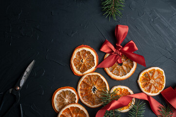 Christmas decoration and wrappung gifts on black background flat lay top view eco sustainable composition with pine branches and dried oranges copy space cute ribbons