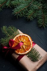 Christmas decoration and wrappung gifts on black background flat lay top view eco sustainable composition with pine branches and dried oranges copy space cute ribbons