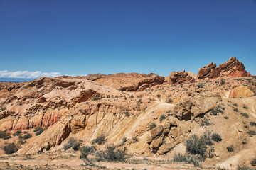 Fototapeta premium Picturesque Skazka Canyon on the southern shore of Issyk-Kul lake, Kyrgyzstan. Travel destination, landmark Kirgiziya. Summer fairytale canyon with colorful rocks and hills. Natural park landscape