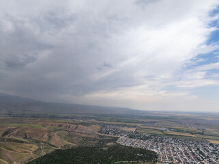 Drone view of the mountains, fields and villages in cloudy weather. Large dark clouds in the sky....