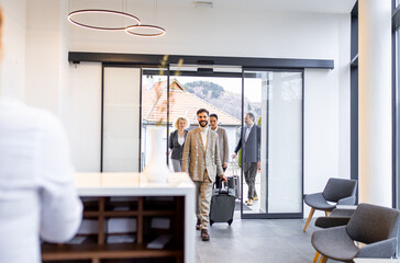 Group of business people arriving in a hotel for a business conference walking towards the...