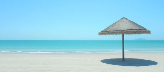 Large thatched umbrella providing shade on a serene beach with turquoise waters and clear blue skies perfect for summer relaxation.