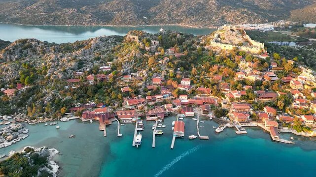 Aerial drone footage of Simena Castle above Kalek&ouml;y Harbor, Antalya Province, Turkey, featuring the Mediterranean coastline at sunset.