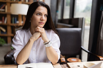 Young Caucasian business woman with long brunette hair working on laptop in cafe. College student using technology , online education, freelance