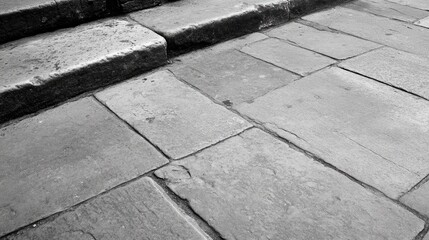 Fototapeta premium Grey brick stone pavement textured surface with steps showcasing urban street design in monochrome tones.