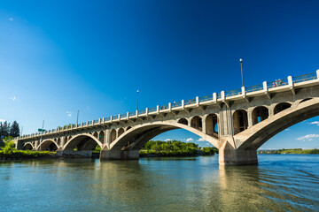 Fototapeta premium A bridge spans a river, with a clear blue sky above