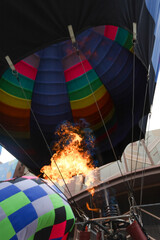 Fototapeta premium Close-up of flames from an inflated hot air balloon with other balloons in the background.