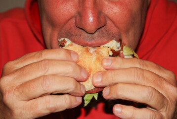 A man biting into a sandwich while eating at a restaurant.