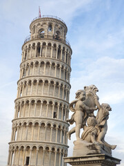 The iconic Leaning Tower of Pisa paired with a cherub statue in the foreground, showcasing the artistry and historical significance of these world-famous landmarks.