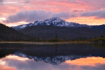 Beautiful autumn landscape during a colorful sunset with mountain lake Arashan where the peak with the first snow is reflected in the water in Kazakhstan. Altai Mountains in Katon Karagay Park.