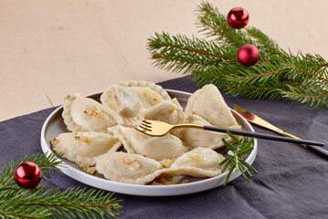 A plate of traditional Polish dumplings (pierogi) stuffed with mushrooms and cabbage, garnished...