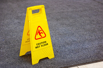 A bright yellow sign displays a caution notice about a wet floor