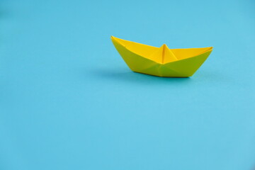 yellow paper ship or paper boats sailing ahead of other ships on blue water.  flat lay with space for text. success, leadership concept