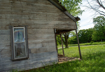 Curtains barely visible thru abandoned house window