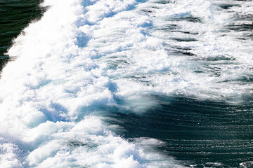 Foamy white ocean waves rolling over deep green water, creating textured patterns and dynamic...