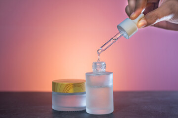 Glass cosmetic jar with serum for face and body skin care. Female beauty tool and cosmetic. Transparent amber glass bottle with pipette and face serum.