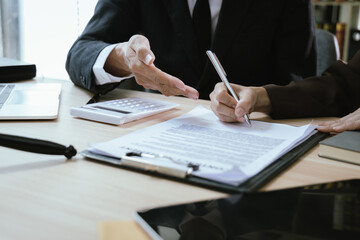 Close up of male lawyer working with contract documents and wooden hammer on table in courtroom....