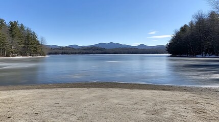 A Calm Lake with Mountains in the Distance and a Sandy Beach in the Foreground