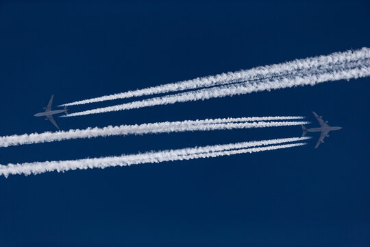 Two air planes with white condensation trails at the deep blue sky
