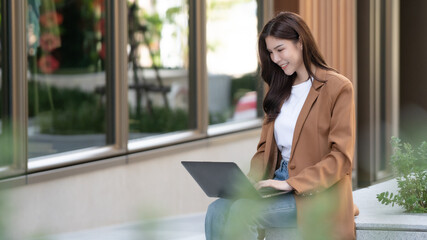 Fototapeta premium Asian businesswoman working remotely outdoors modern workspace engaging atmosphere focused viewpoint professional lifestyle