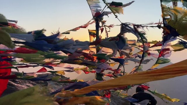 Inside of a web of Tibetan Buddhist prayer flags that waving in a strong wind of a Himalayan mountain peak. in the background the sun the rise behind the range