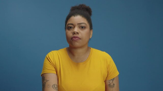Women with sealed mouth sharply rip off sticky tape from lip. Don't be silent. Domestic abuse and harassment concept. Isolated on blue background
