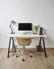 Office desk with computer equipment on it and also office chair located in an office room with bright white walls