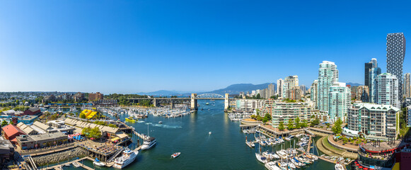 Panoramic Aerial View of Granville Island in False Creek with modern city skyline and mountains in background. Downtown Vancouver, British Columbia, Canada.