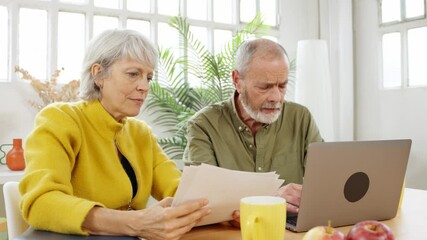 Mature couple discussing paperwork at home - Powered by Adobe