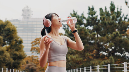 Drinking water, outdoor and woman with fitness, wellness and rest with workout. Japanese person,...