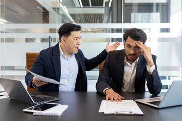 Angry colleague yelling at a stressed employee in a modern office setting. This scene captures...