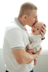 dad holds a newborn baby in his arms, gently hugging and kissing, father and newborn son on a white background