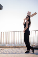Stylish female model posing confidently with a blazer draped over her shoulder, standing on a...