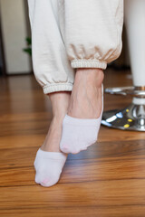 Women's legs in white short cotton socks on a white background. Ladies in sports socks