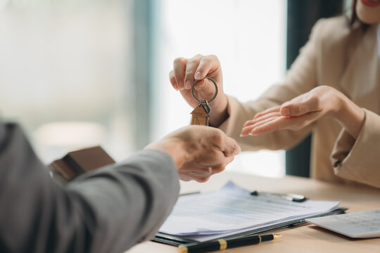 Key Handover: Real Estate Agent handing house keys to a happy new homeowner. A symbol of new beginnings and successful property transactions. - Powered by Adobe