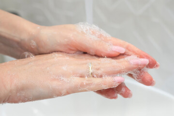 Fototapeta premium Close-up shot of a woman washing her hands using soap