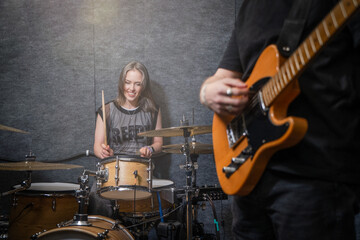 Female drummer plays drum set in soundproof music studio, her smile reflecting joy of music, while...